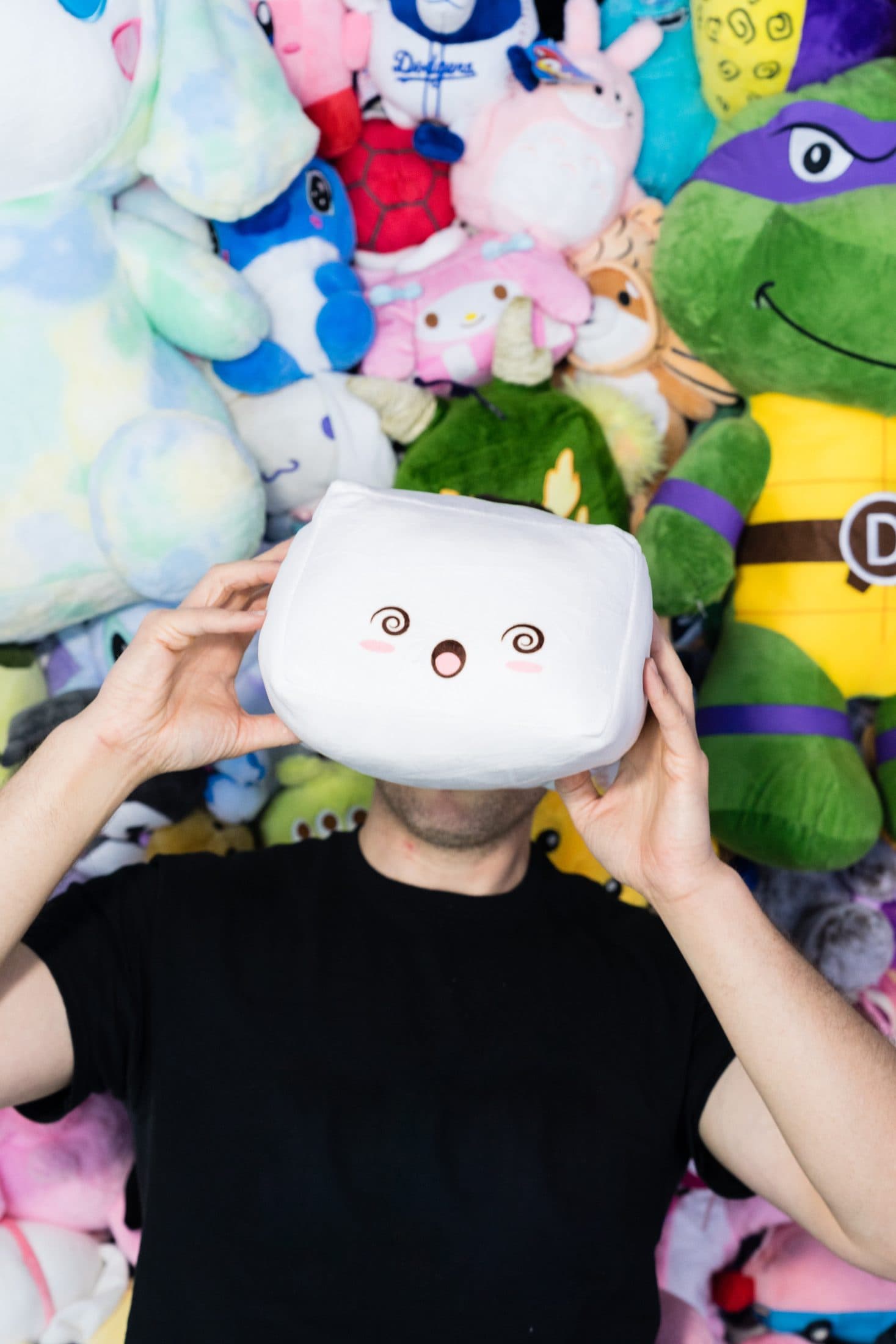 A guest playfully holding a large square plush in front of their face.