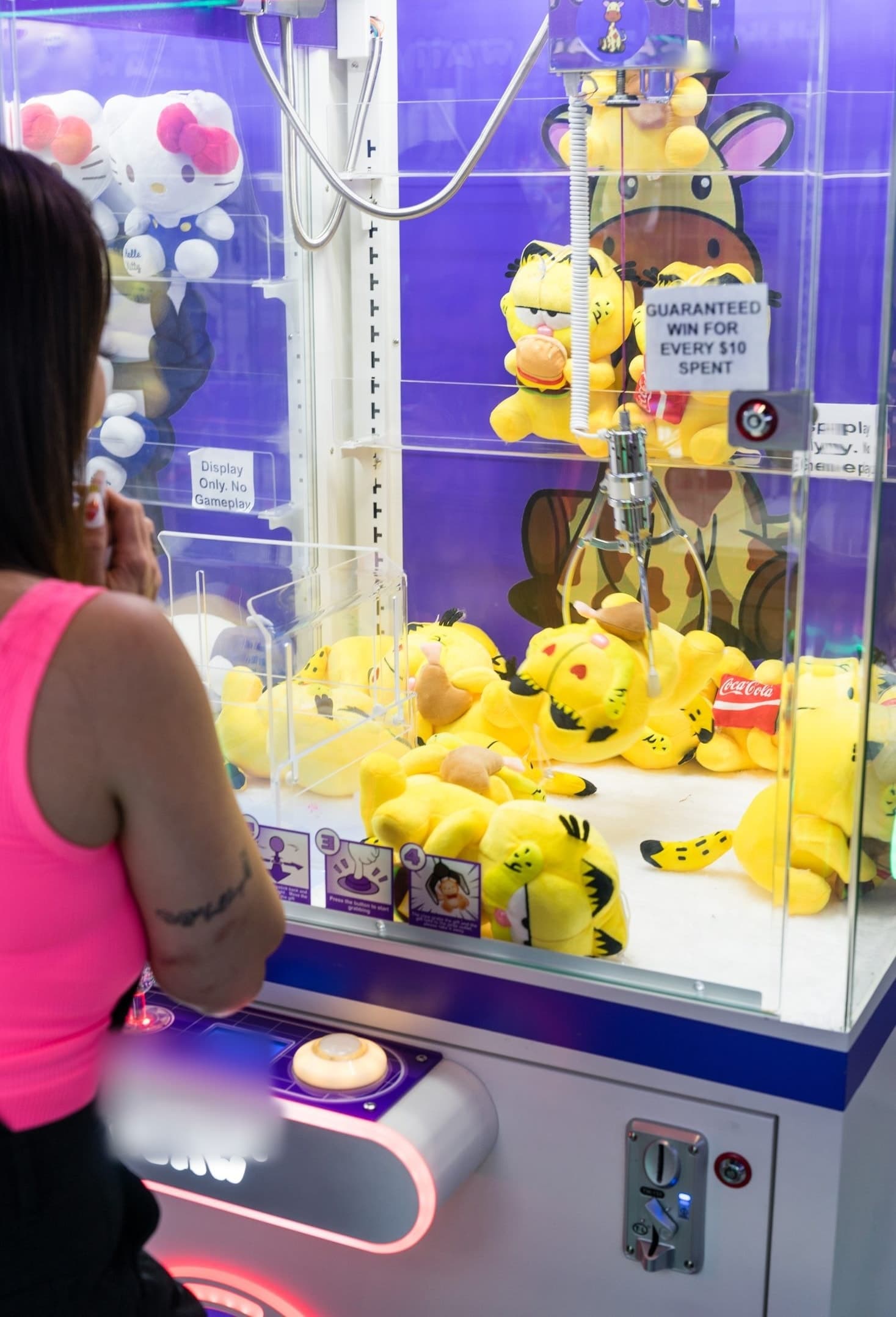 A player lining up the claw over a machine stocked with yellow plush characters.